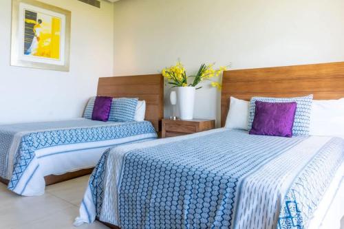 two beds in a room with purple and blue sheets at 4-BR paradise view in Acapulco in Acapulco
