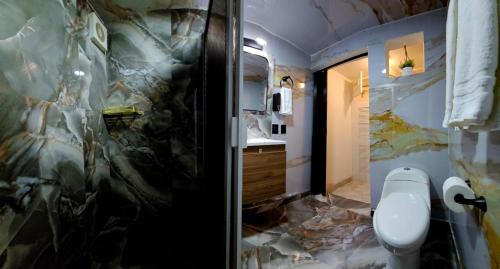 a bathroom with a toilet and a marble wall at Book & Sleep Cancun in Cancún