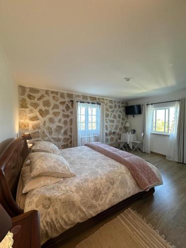 a bedroom with a large bed and two windows at Terra Luso in Cadaval
