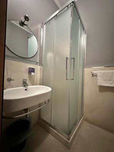 a bathroom with a shower and a sink and a mirror at Ostello City In Hostel B&B in Catania