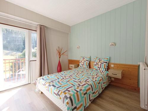 a bedroom with a bed and a large window at Gîte les Égravines in Mijoux