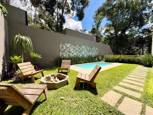 a backyard with two chairs and a fire pit and a pool at Casa 10 Floresta Boa Vista - Piscina Privativa, Adega e Conforto em 4 suítes in Teresópolis