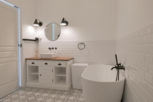 a white bathroom with a tub and a sink at "La Villa Gozforn" avec piscine privée, plages et commerces de la station balnéaire de Beg-Meil à pied! in Fouesnant