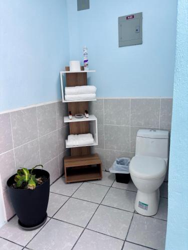 a bathroom with a toilet and a shelf with towels at La 10a de Las Charcas in Guatemala