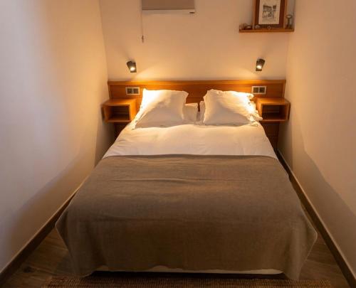 a bedroom with a bed with white sheets and pillows at El Apartamento de Hervás in Hervás
