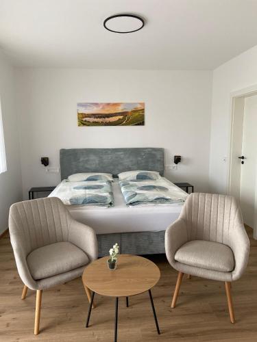 a bedroom with a bed and two chairs and a table at Weingut Lehnert-Später in Piesport