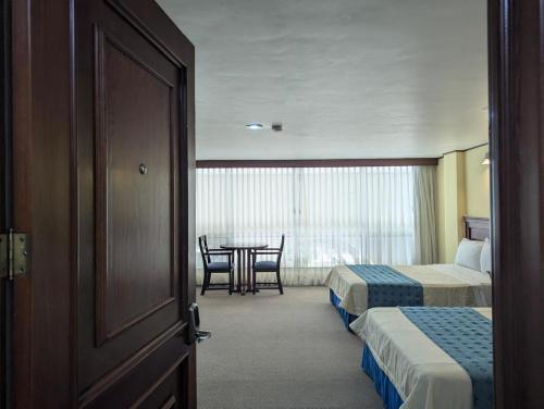 a hotel room with two beds and a table at Hotel Tehuacan Plaza in Tehuacán