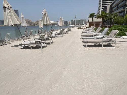 a row of lounge chairs on a beach at Luxury 2 Bedroom Apartment - Private Beach - Emaar Beach Vista in Dubai