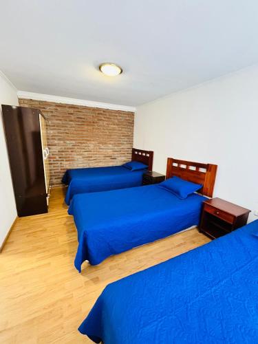 three beds in a room with blue sheets at Departamento Independiente Altavista Hostal- 6 personas in Rancagua