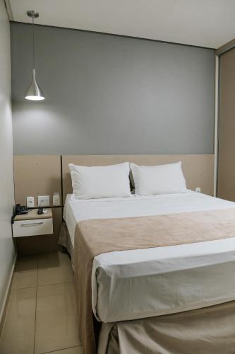 a bedroom with a large bed and a night stand at Grande Hotel Ipatinga in Ipatinga