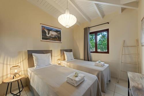 two beds in a room with a window at Villa The Hidden Palm, Piscadera, Private Pool in Willemstad