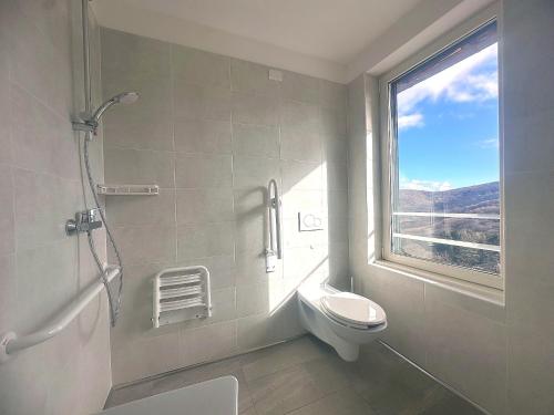 a bathroom with a shower and a toilet and a window at vitalArmonie Retreat in Marzio
