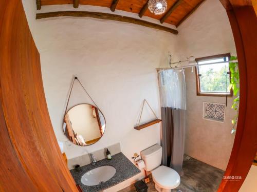 a bathroom with a sink and a toilet and a mirror at Sítio Embaú in Carrancas
