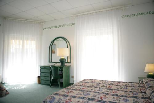 a bedroom with a bed and a dresser and a mirror at Hotel Diana in Grado