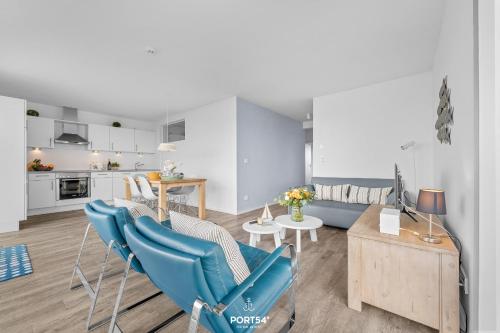 a living room with blue chairs and a kitchen at Ferienwohnung Albatros Olpenitz in Olpenitz