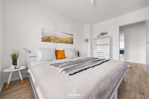 a white bedroom with a large bed with orange pillows at Ferienwohnung Albatros Olpenitz in Olpenitz