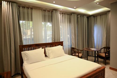 a bedroom with a bed and a table and a window at Neon Hotel in Kampala