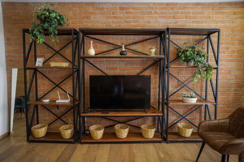 a black entertainment center with a television in front of a brick wall at Luxury 3BR Pool and Gym in Roma in Mexico City