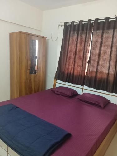 a bedroom with a bed with purple sheets and a window at Akshara Ac 1 bhk in Hinjewadi