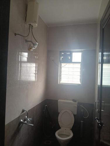a bathroom with a toilet and a window at Akshara Ac 1 bhk in Hinjewadi