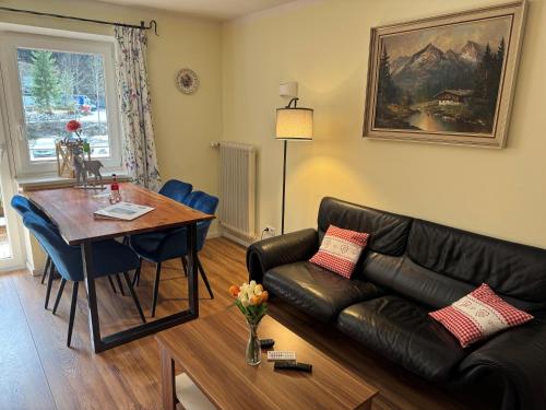 a living room with a leather couch and a table at Alpenlodge Ferienwohnung 5 in Thiersee