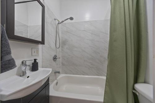 a bathroom with a sink and a shower with a shower curtain at Times Square Retreat with Private Bathroom and Kitchenette in New York