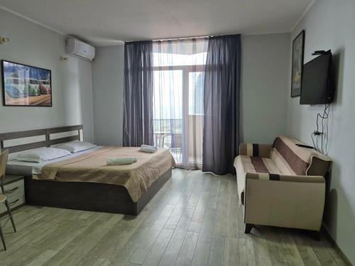 a bedroom with a bed and a couch and a window at TOWERS Apartament in Batumi