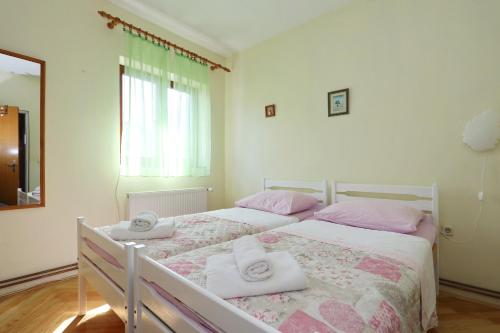 a white bedroom with two beds with pink pillows at Apartment Tea with Sea View in Petrcane