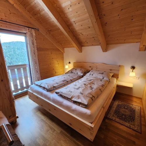 a large bed in a room with a large window at Auszeit Almhaus Schmalzbauer in Sankt Andrä