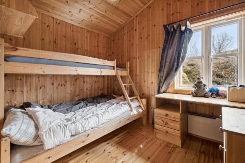 a bunk bed in a wooden room with a window at Hytte med peis utsikt & lakseelv rett nedenfor! in Lødingen