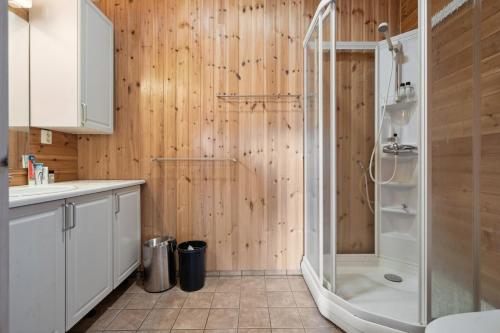 a bathroom with a shower with wooden walls at Hytte med peis utsikt & lakseelv rett nedenfor! in Lødingen