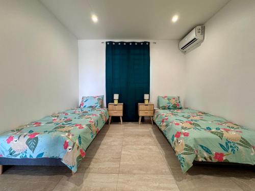a bedroom with two beds and a table with two lamps at Appartement Mango in Rivière-Salée