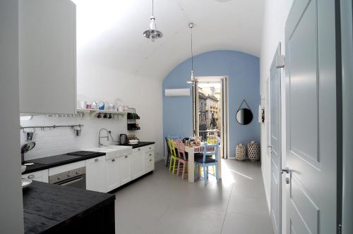 eine Küche mit weißen Schränken und einer blauen Wand in der Unterkunft A Casa di Anna in Neapel