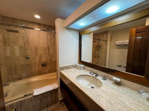 a bathroom with a sink and a mirror and a tub at Perfect Place Velas Vallarta Resort in Puerto Vallarta