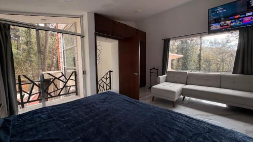 a bedroom with a bed and a couch and a window at Villa 1 TRES SENDEROS in Omitlán de Juárez