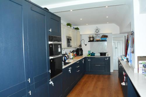a kitchen with navy blue cabinets and wooden floors at Peaceful Room Overlooking Nature & Parking in Bloxwich