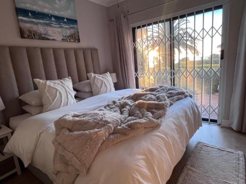 a bed with a blanket on it in a room with a window at Beachside Bliss Gordons Bay in Gordonʼs Bay