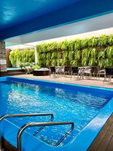 a swimming pool with tables and chairs in a building at Hotel Rieger in Balneário Camboriú