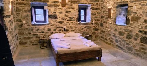 a bedroom with a bed in a stone wall at Pyrgos Mitsakou in Vathia