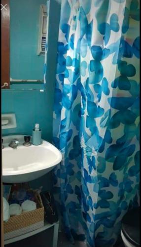 a bathroom with a sink and a blue shower curtain at San bernardo edificio frente al mar in San Bernardo