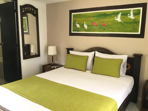 a bedroom with a bed with green and white pillows at Hotel Campestre La Potra in Villavicencio