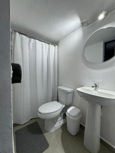 a white bathroom with a toilet and a sink at The Boat House Cancun in Cancún