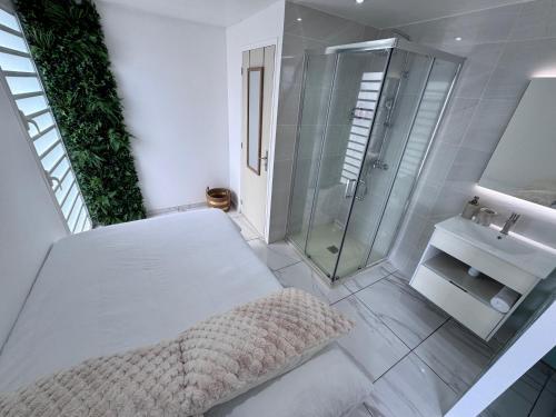 a white bathroom with a shower and a sink at Studio Splash 2 personnes piscine chauffée in Rivière-Salée