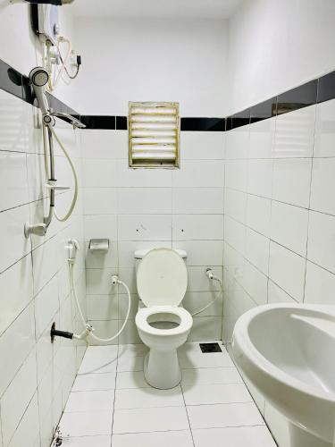 a white bathroom with a toilet and a sink at Kandy Green HillTop Hotel in Kandy