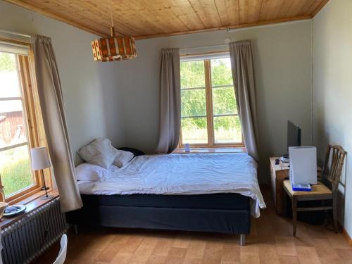 a bedroom with a bed and two windows at Maple Cottage in Docksta