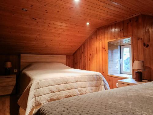 two beds in a wooden room with a window at Casa do Padrinho in Teixeira de Baixo