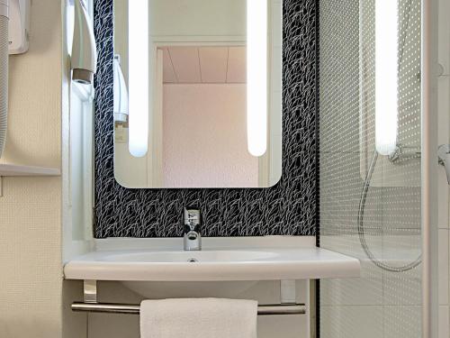 a bathroom with a sink and a mirror at ibis Lorient Centre Hôtelier in Caudan