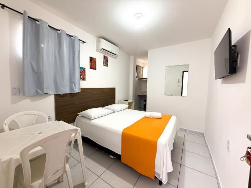 a bedroom with a bed and a table and a tv at Pousada Granville in Campina Grande