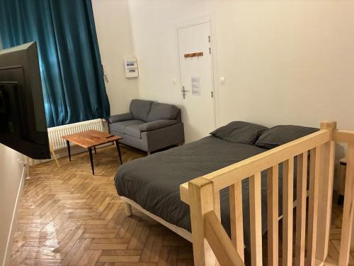 a bedroom with a bed and a couch and a television at Duplex with Jacuzzi - Grand place Arras in Arras