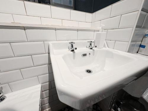 a white sink in a bathroom with white tiles at Edinburgh Town Apartment in Edinburgh